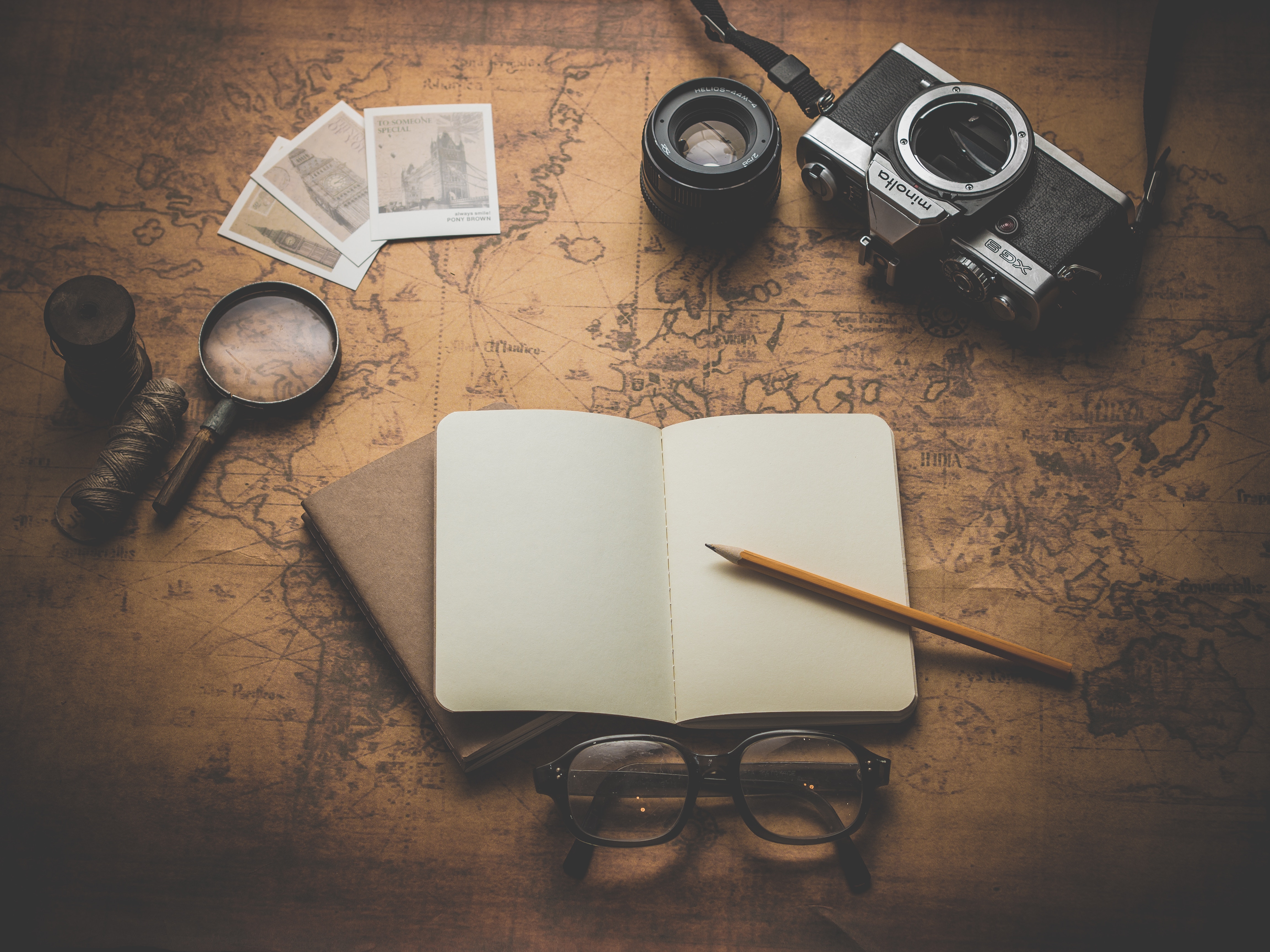 Travel flat lay with map, camera, journal, and magnifying glass