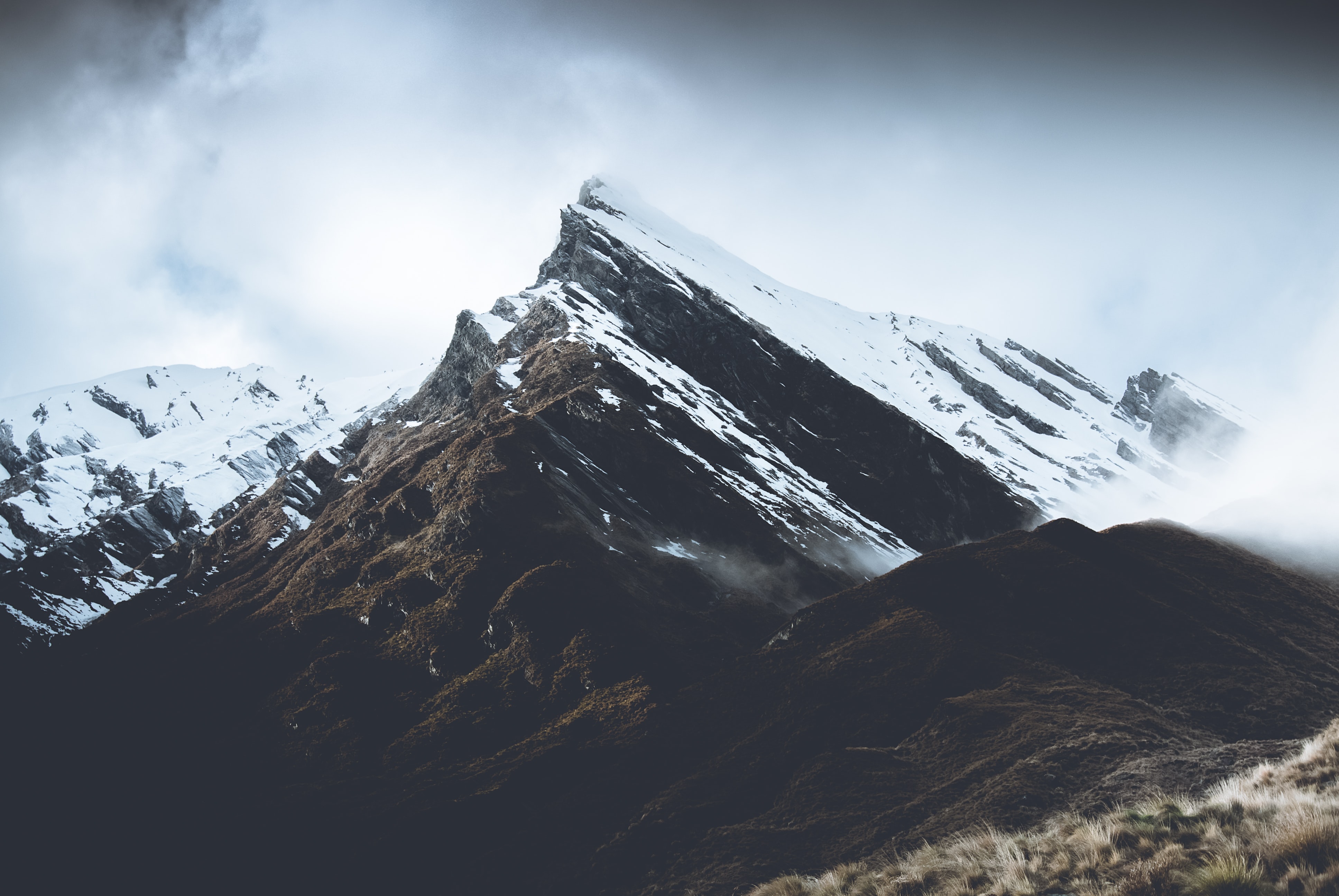 Snow-capped mountain peak in moody clouds