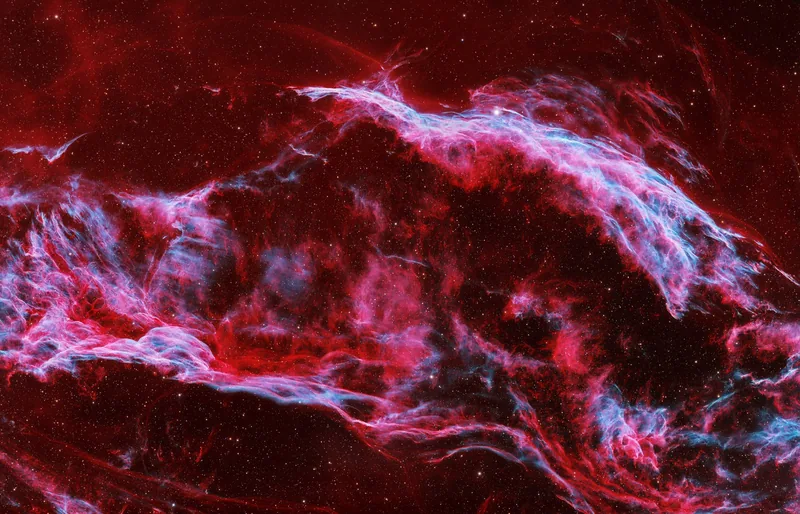 Filaments of the Veil supernova remnant in red and cyan across a dark star field