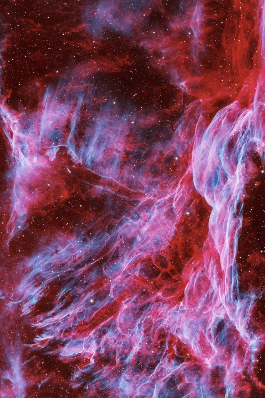 A chaotic web of crossing filaments in the Veil Nebula, cyan braided through crimson