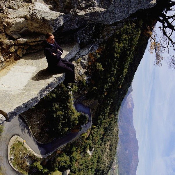Man sitting on a cliff edge overlooking a gorge