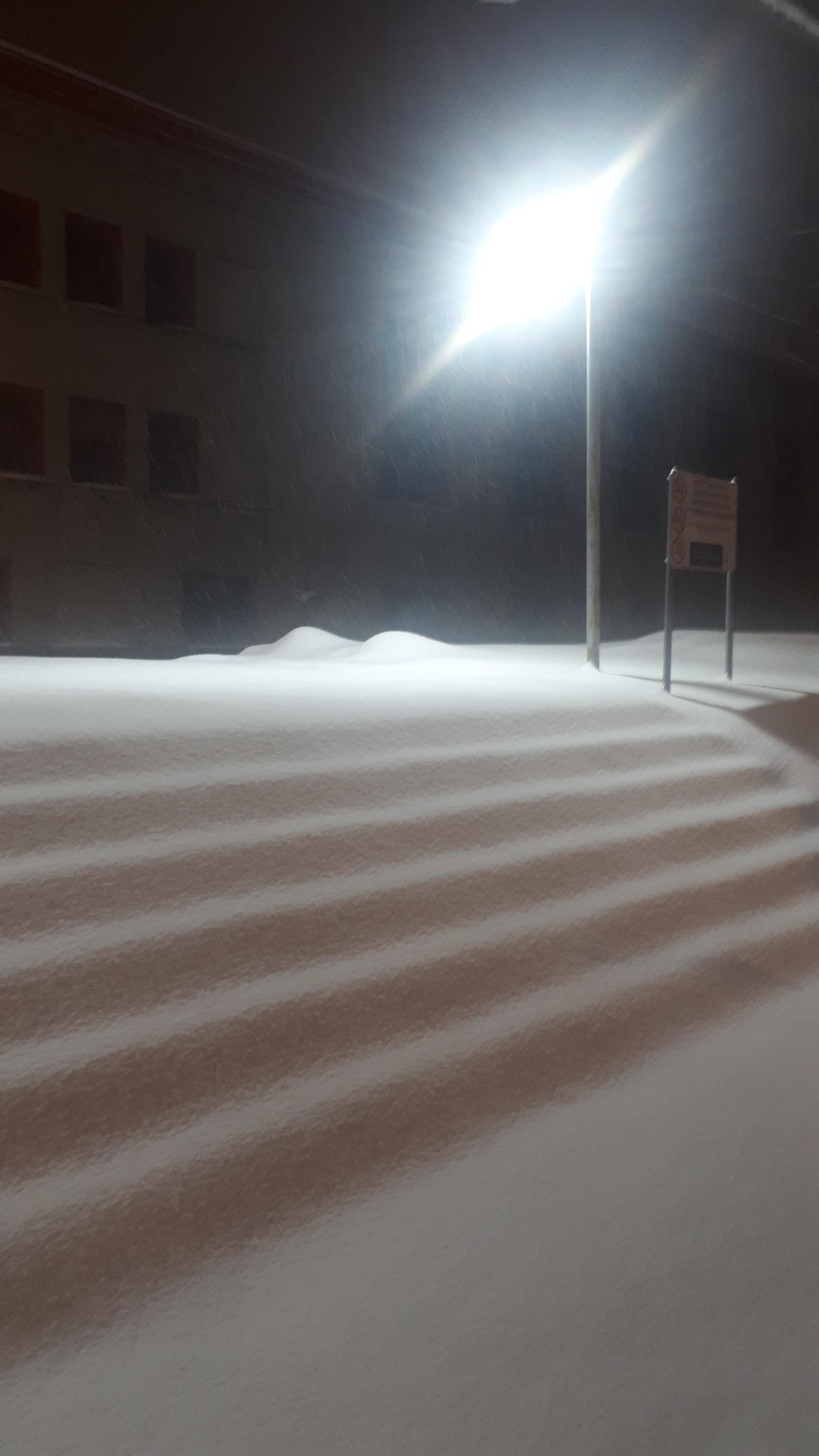 Deep snow at night under a street lamp